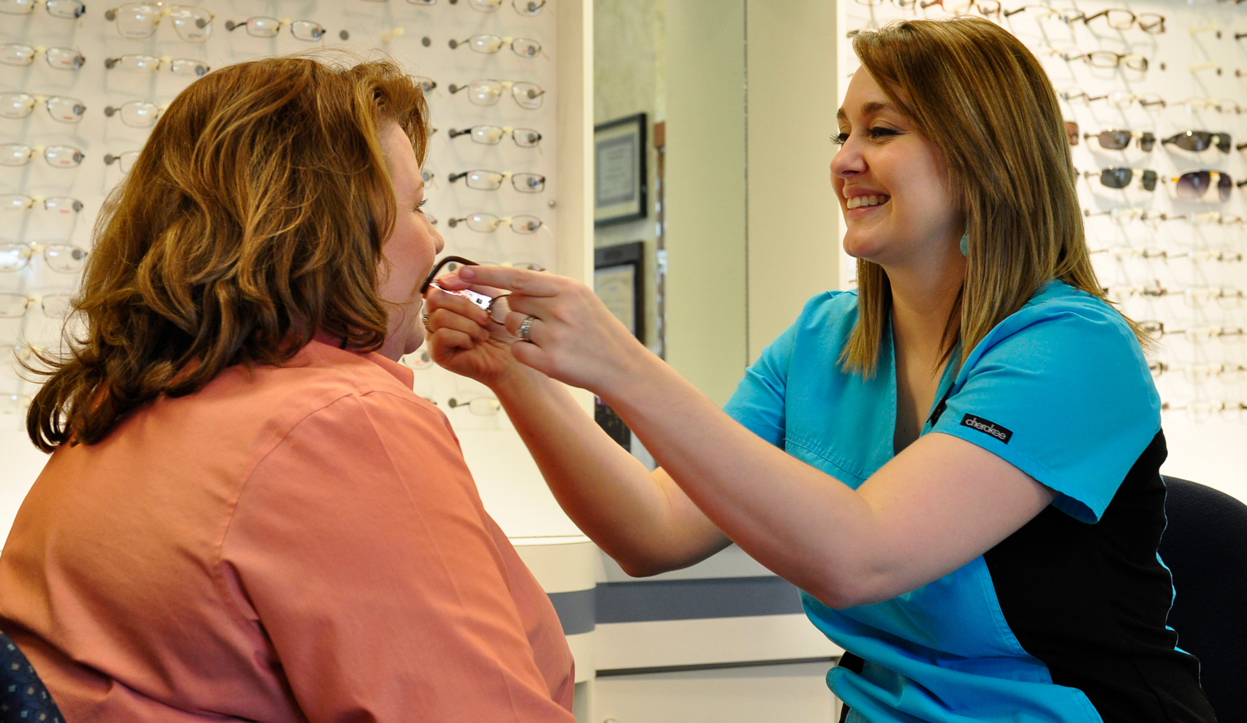 Professional Eye Employee Helping Patient With New Glasses