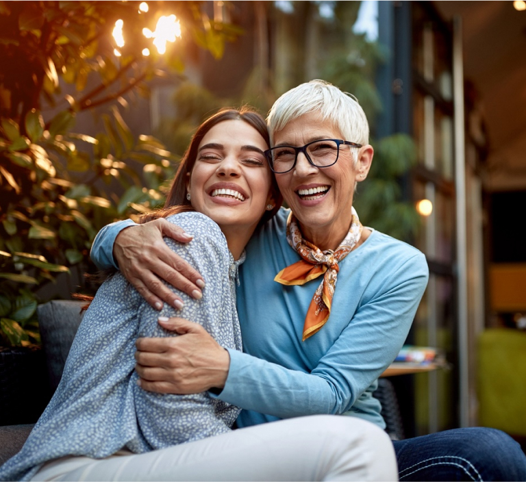 Mother And Adult Daughter Hugging And Smiling Together