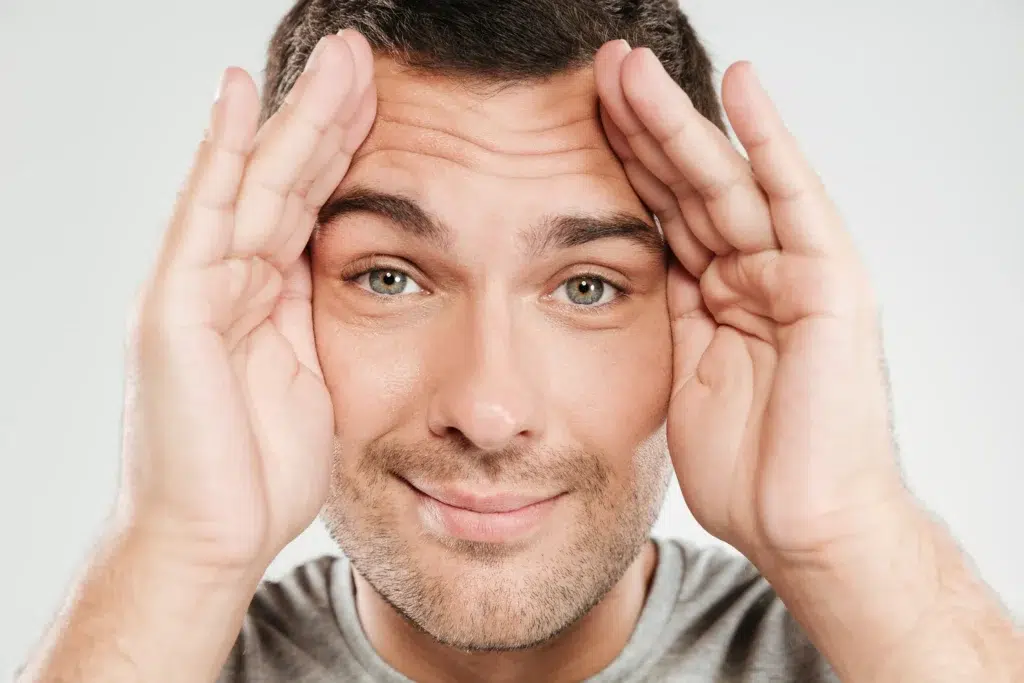 Smiling young man showing his eyes